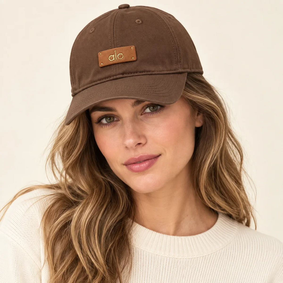Model wearing metal logo baseball cap on head